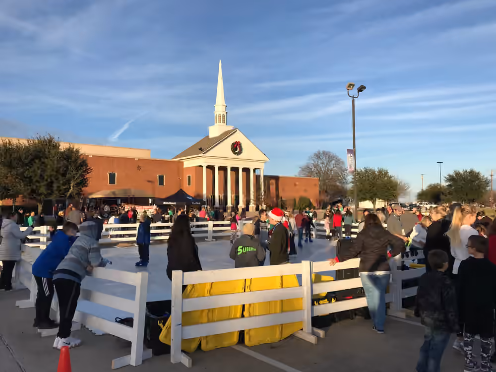 Families using a portable rink beside a church
