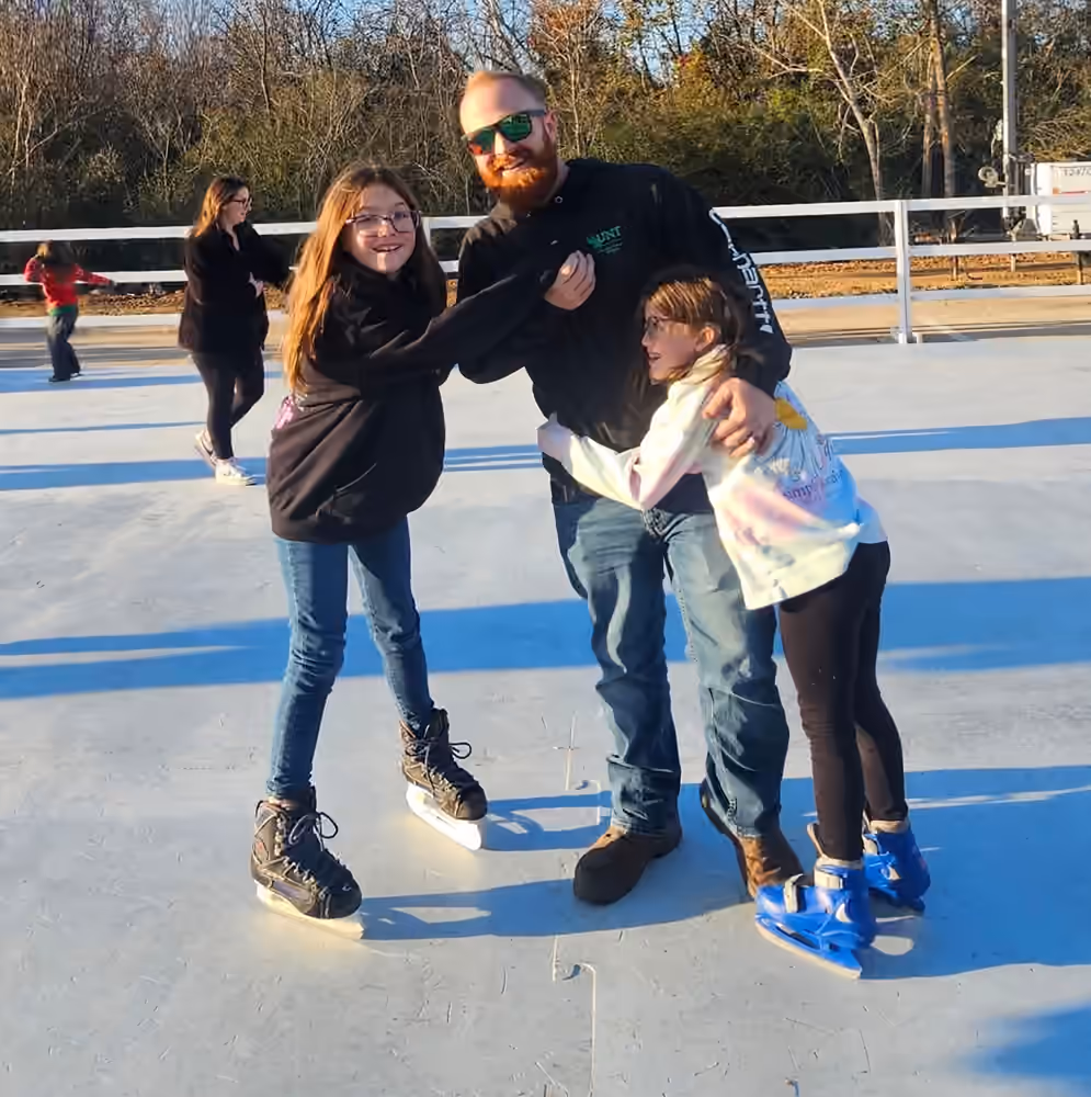 A family sharing a playful moment on the synthetic ice rink