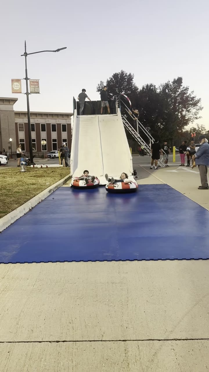 Two guests racing down the Classic Holiday portable snow tube slide